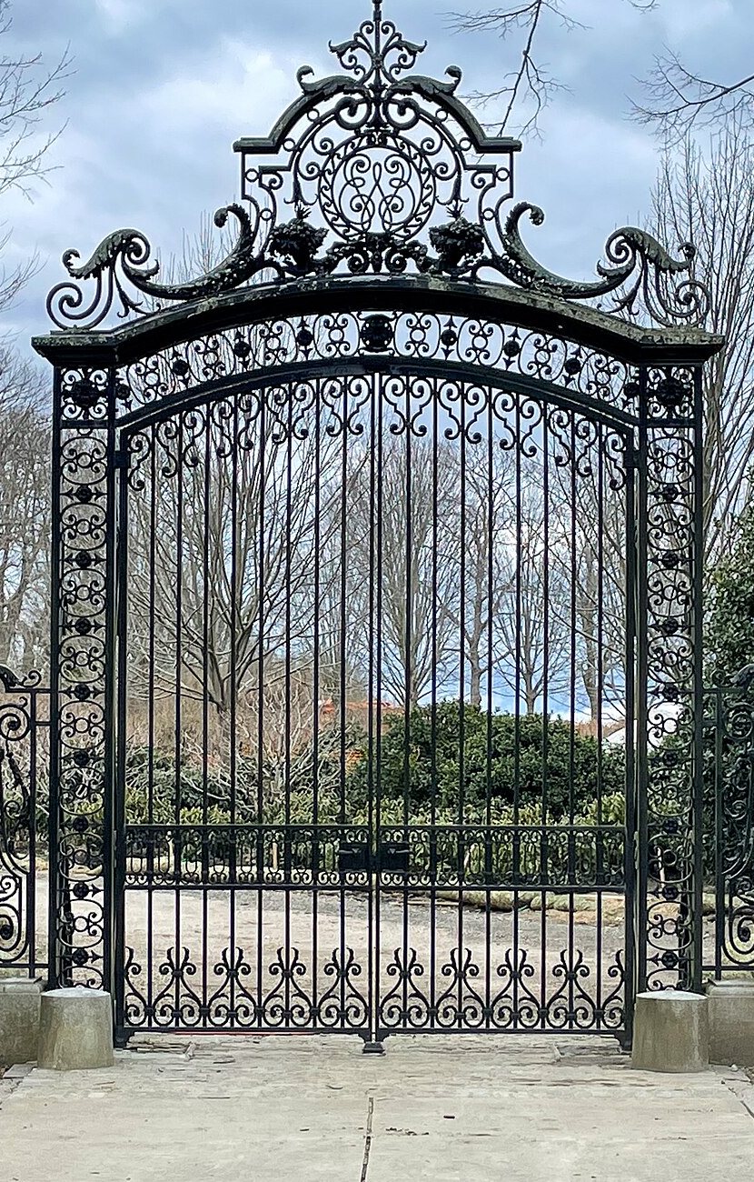 A tall wrought iron estate gate between stone piers